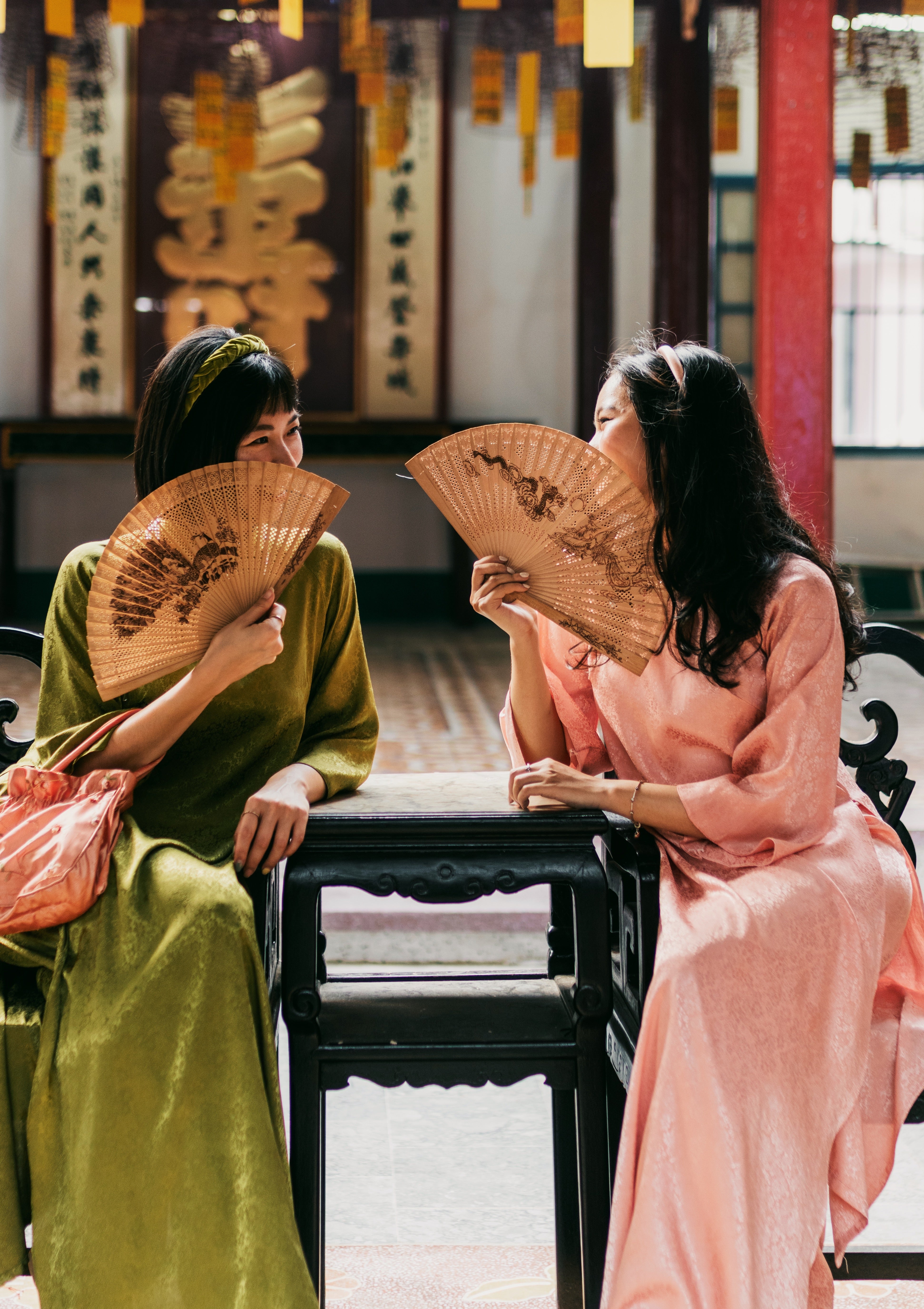 Central_Vietnam_Hoi_An_Davina_and_Thao_Sitting_on_Chairs_Holding_Fans.jpg